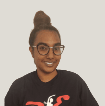 Headshot of a Bollywood dance instructor wearing a Dance Expression shirt with glasses and hair in a bun.