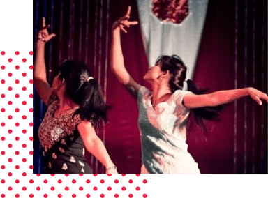 Two dancers striking a pose on a stage in black and green indian attire.